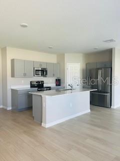 A modern kitchen features gray cabinets, stainless steel appliances, and a central island with seating — 1005 FORESHORE LANE, HAINES CITY, FL