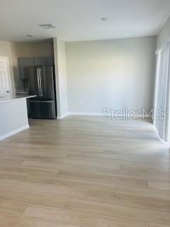 An open-concept room with light wood-look flooring, a stainless steel refrigerator, and a kitchen counter — 1005 FORESHORE LANE, HAINES CITY, FL