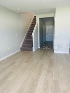 An interior view shows a room with light wood-look flooring, a staircase, and a doorway — 1005 FORESHORE LANE, HAINES CITY, FL