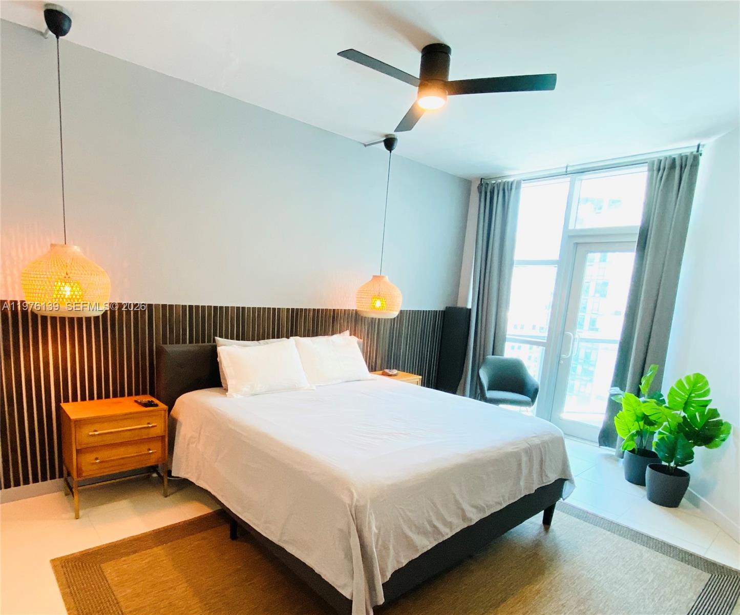 A bedroom features a bed with pendant lights, a slatted headboard, and a balcony door — 3301 NE 1st Ave # H1608, Miami FL 33137, MIAMI, FL