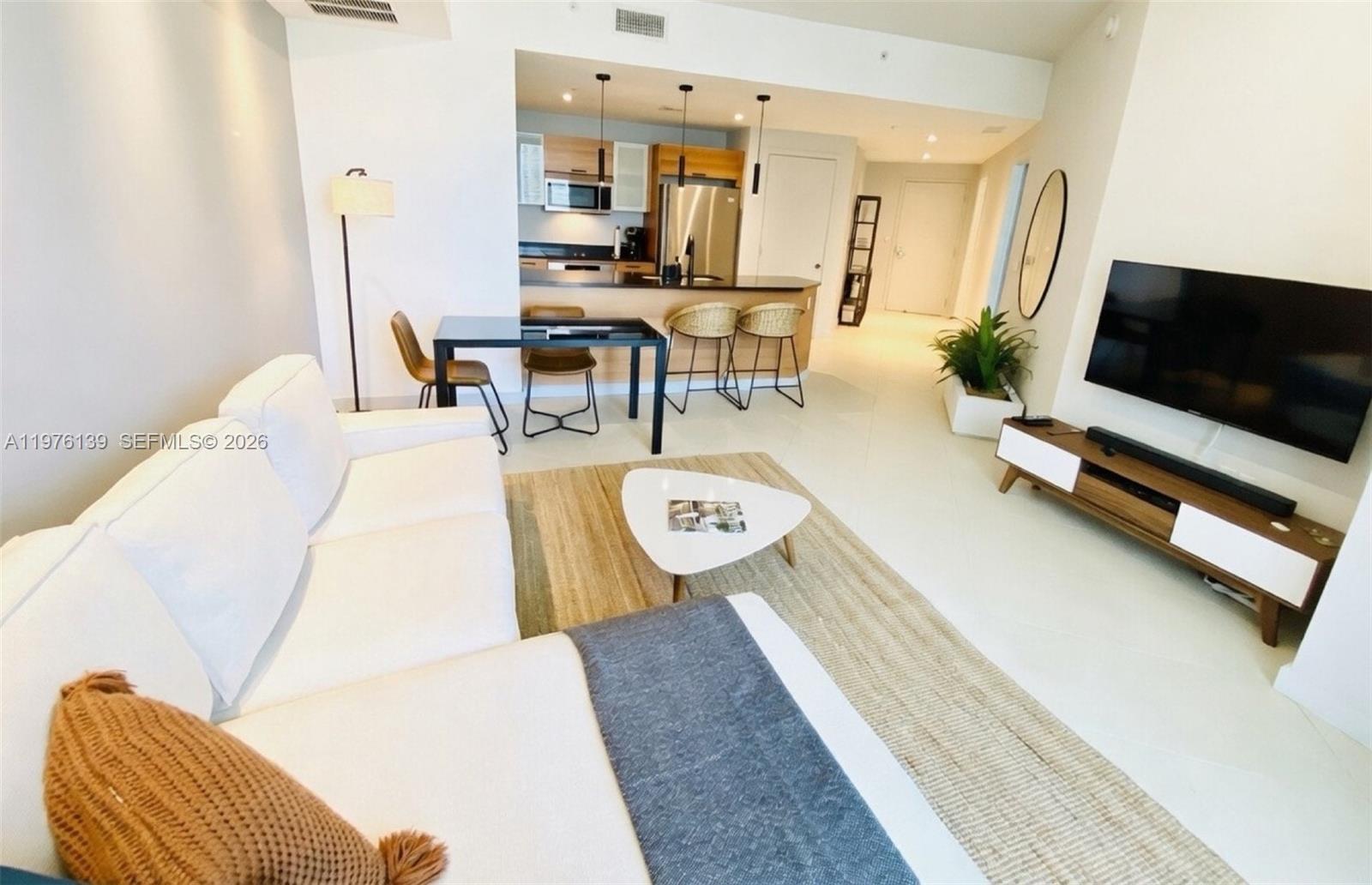 A living room features a white sofa, a coffee table, and an open-concept kitchen area — 3301 NE 1st Ave # H1608, Miami FL 33137, MIAMI, FL