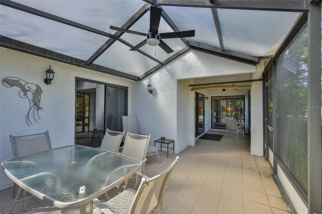 A screened-in patio features a glass-top dining set, a ceiling fan, and tiled flooring — 1305 SPRY COURT, SUN CITY CENTER, FL