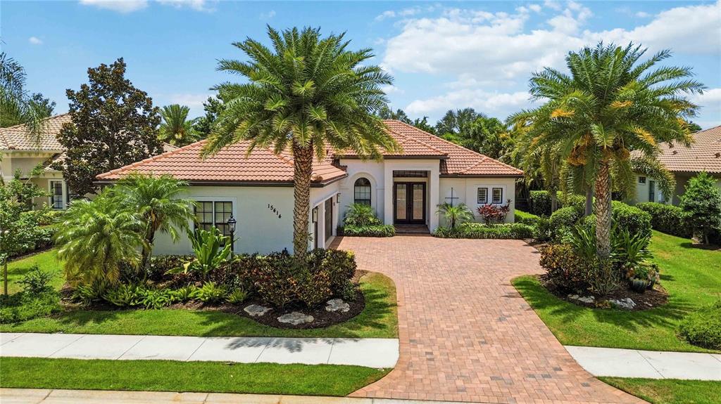 A single-story house with a tiled roof, brick driveway, and two large palm trees — 15414 LEVEN LINKS PLACE, BRADENTON, FL