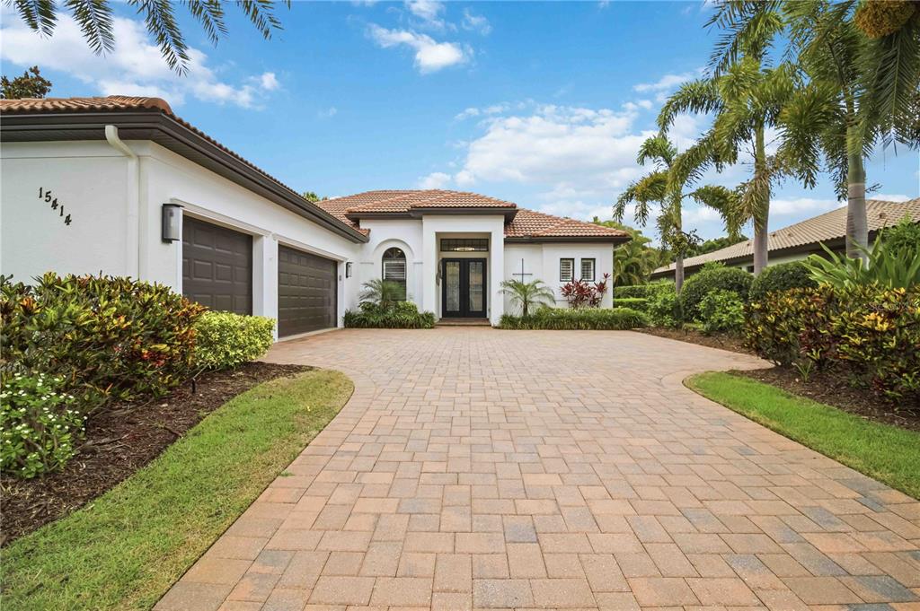 A single-story white house with a tile roof, two-car garage, and a paved driveway — 15414 LEVEN LINKS PLACE, BRADENTON, FL