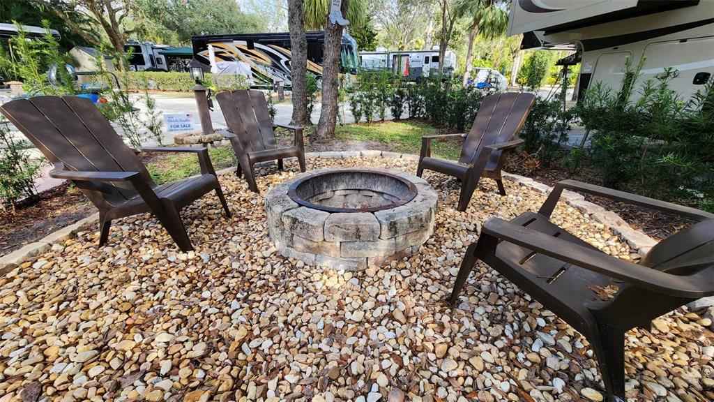 A stone fire pit sits in a gravel area surrounded by four dark plastic chairs — 187 LONGHORN DRIVE, LAKE WALES, FL