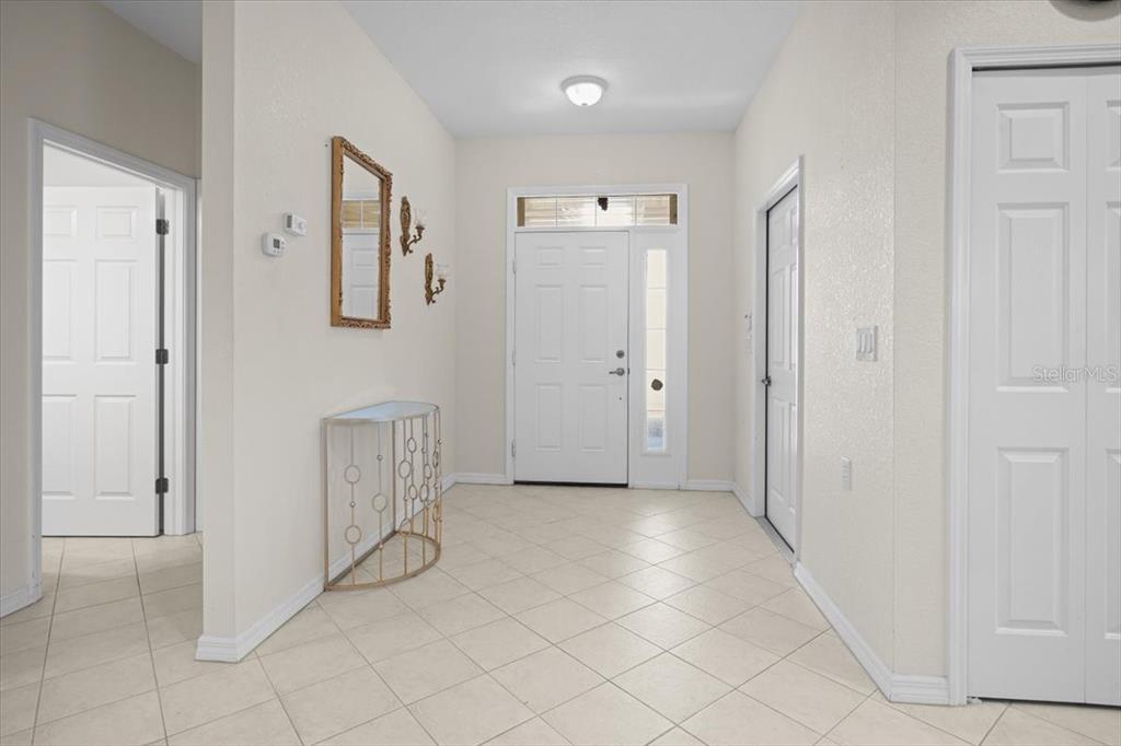 A bright entryway features light tile flooring, a white front door, and a gold console table — 24181 GREEN HERON DRIVE UNIT 84, PUNTA GORDA, FL