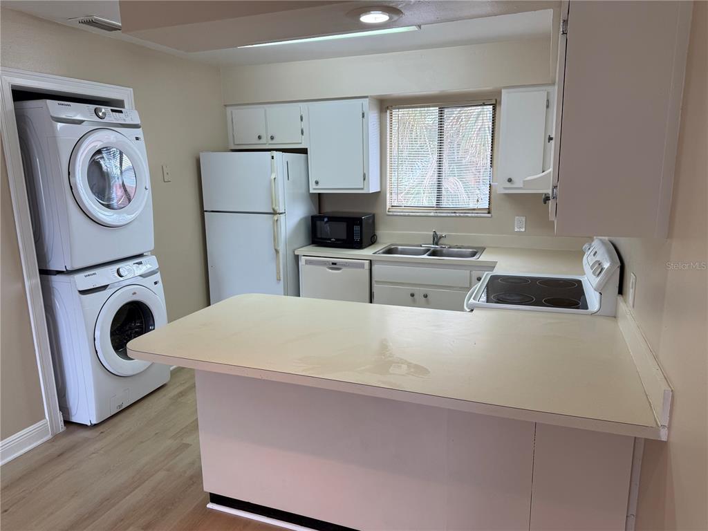 A kitchen features white cabinets, a stacked washer and dryer, and a breakfast bar — 7340 SWALLOW RUN UNIT 7340, WINTER PARK, FL