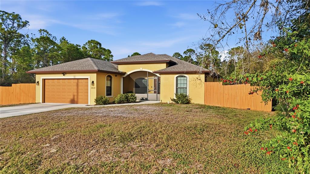 A yellow single-story house with a two-car garage and a wooden fence — 3018 BARRY ROAD, NORTH PORT, FL