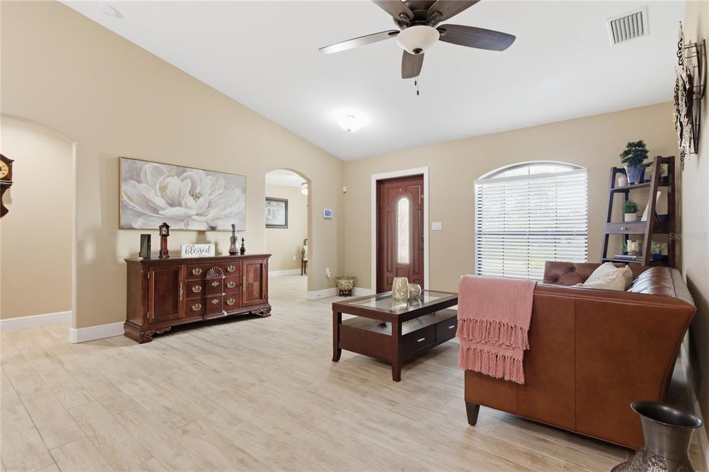 A living room with light tile flooring, a brown leather sofa, and a wooden console table — 3018 BARRY ROAD, NORTH PORT, FL