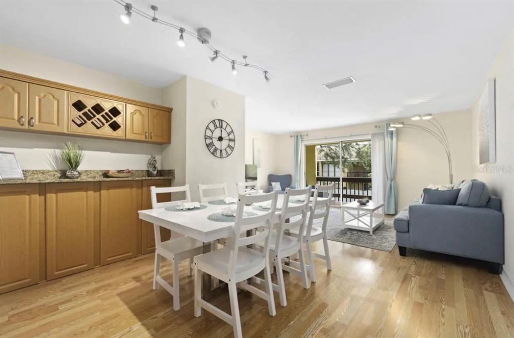 A dining room with a white table and chairs, light wood floors, and a wet bar — 3469 CLARK ROAD UNIT 268, SARASOTA, FL