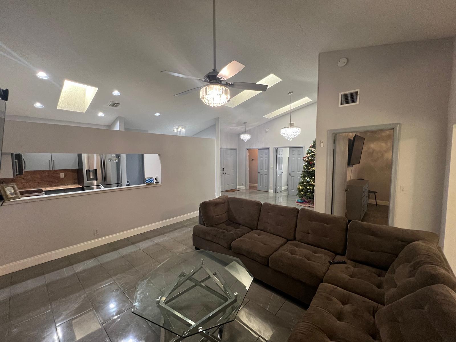 A living room features a brown sectional sofa, tile floors, and a pass-through kitchen window — 4241 Green Forest Way, Boynton Beach FL 33436, BOYNTON BEACH, FL