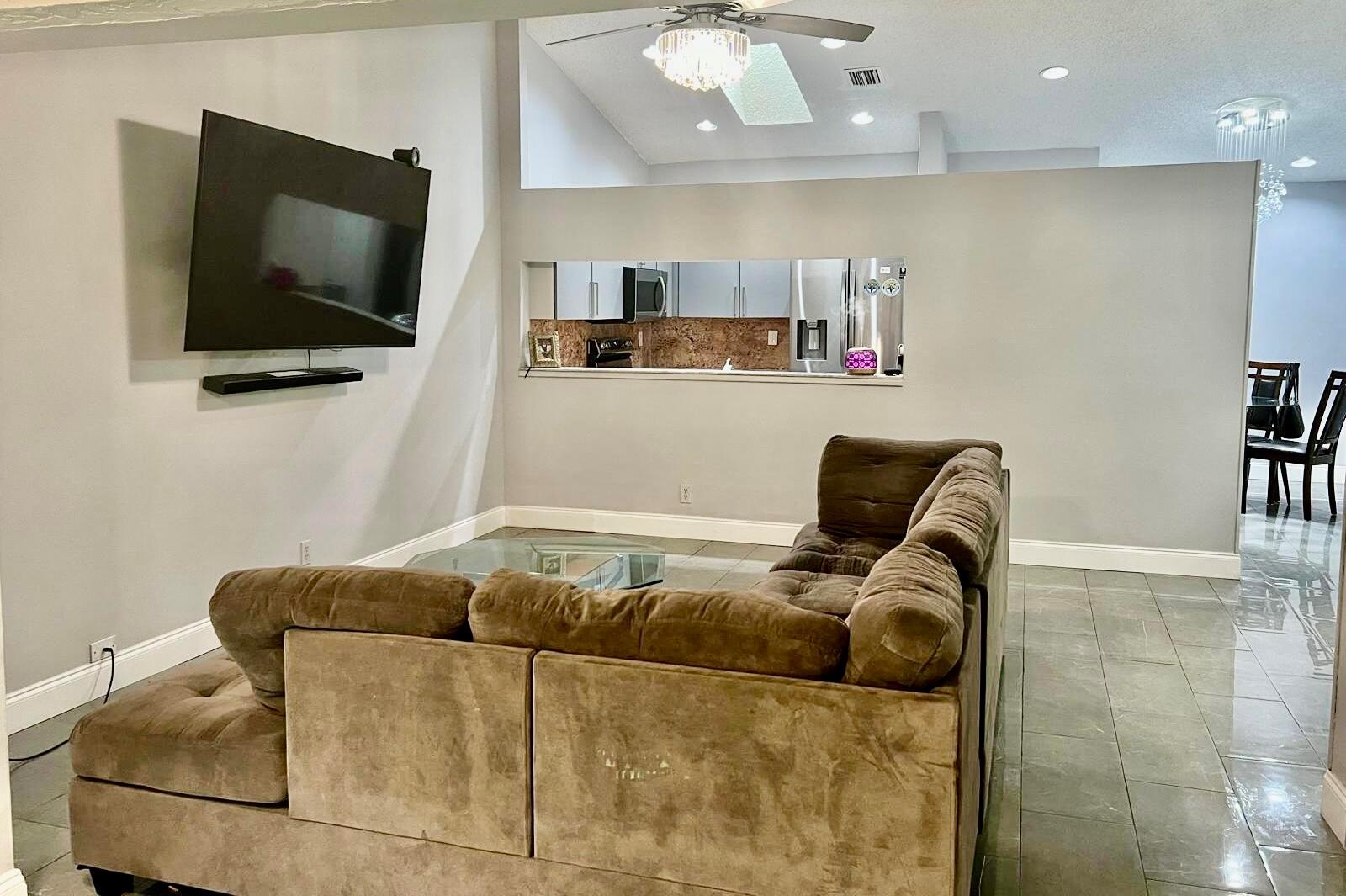 A living room features a large brown sectional sofa, a wall-mounted television, and tile flooring — 4241 Green Forest Way, Boynton Beach FL 33436, BOYNTON BEACH, FL