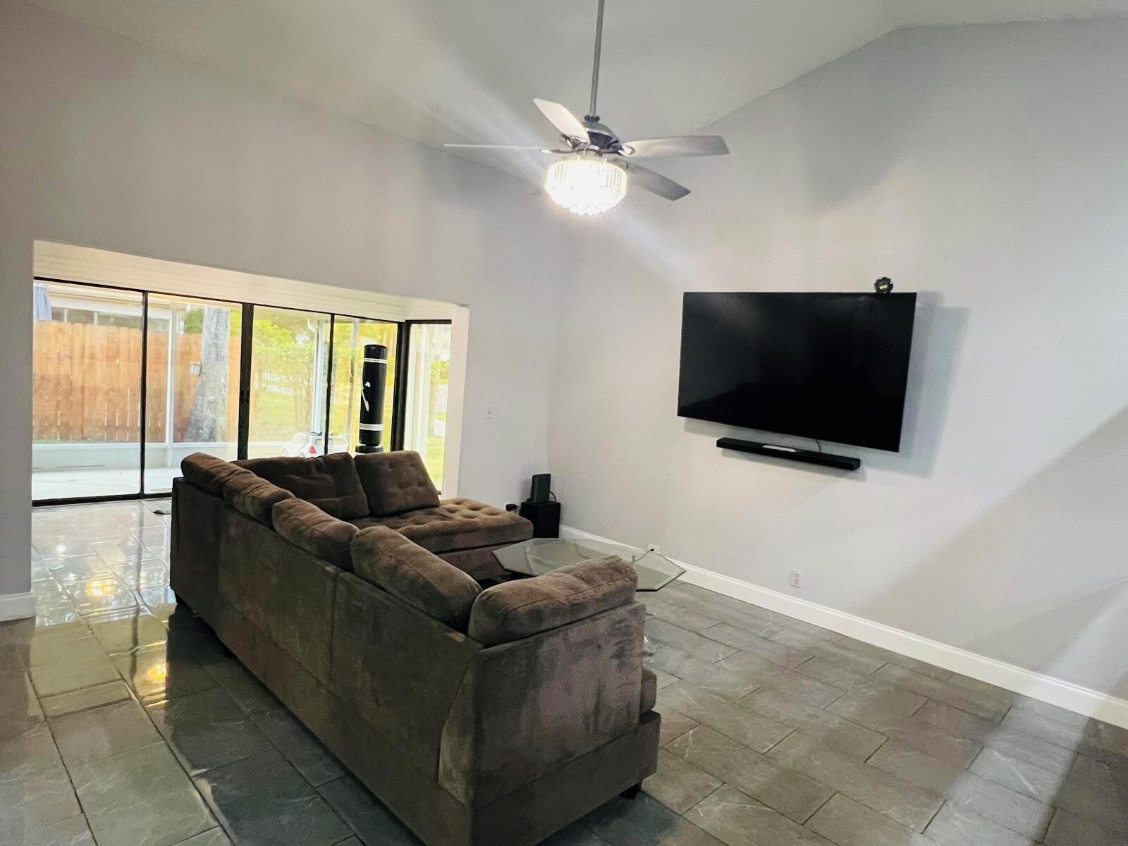 A living room features a large sectional sofa, a wall-mounted television, and tile flooring — 4241 Green Forest Way, Boynton Beach FL 33436, BOYNTON BEACH, FL