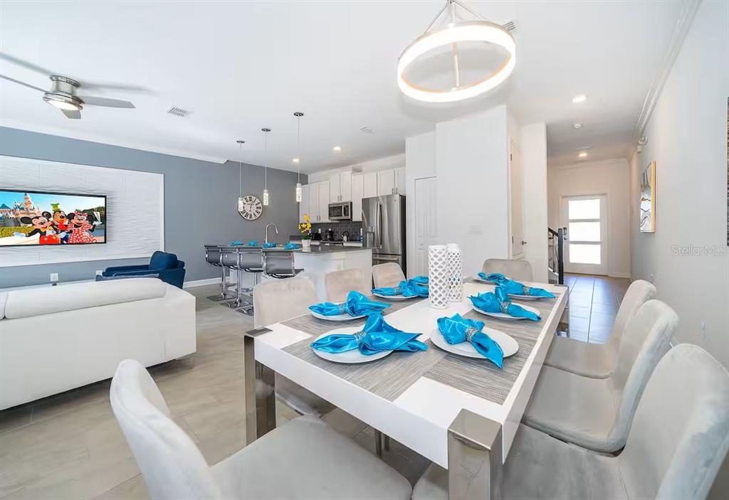 A dining area with a white table and chairs sits in front of an open kitchen — 4188 PARAGRAPH DRIVE, KISSIMMEE, FL