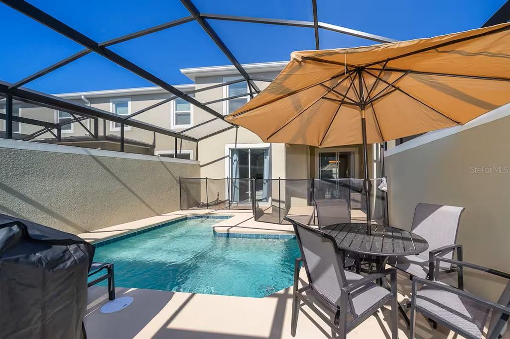 A screened-in patio features a small swimming pool, a dining set, and a tan umbrella — 4188 PARAGRAPH DRIVE, KISSIMMEE, FL