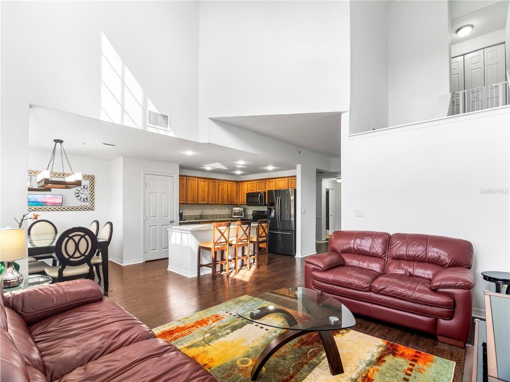 An open-concept living room and kitchen feature high ceilings, hardwood floors, and red leather sofas — 126 S OBRIEN STREET, TAMPA, FL