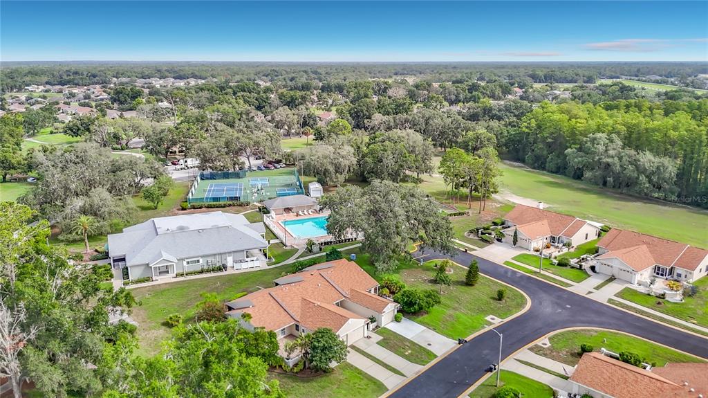 An aerial view shows a residential neighborhood with a swimming pool, tennis courts, and houses — 13130 GREENVIEW COURT, HUDSON, FL