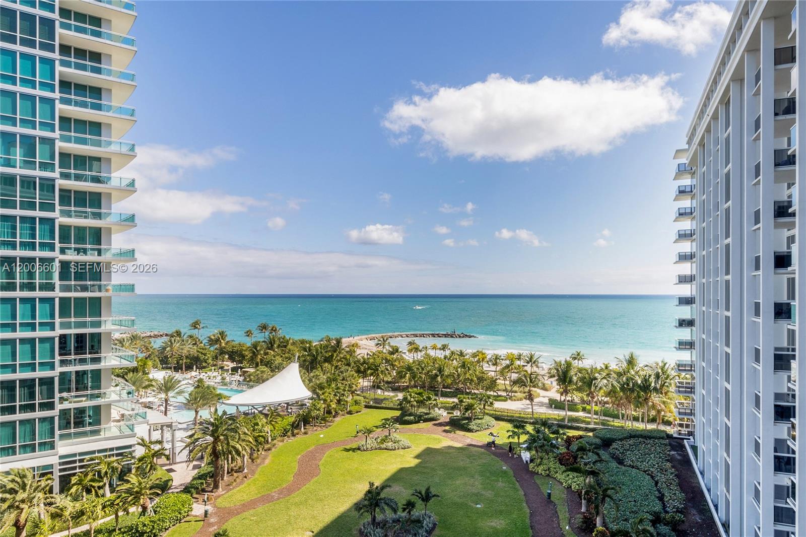 An elevated view shows a lush green courtyard between two tall residential buildings overlooking the ocean — BAL HARBOUR, FL