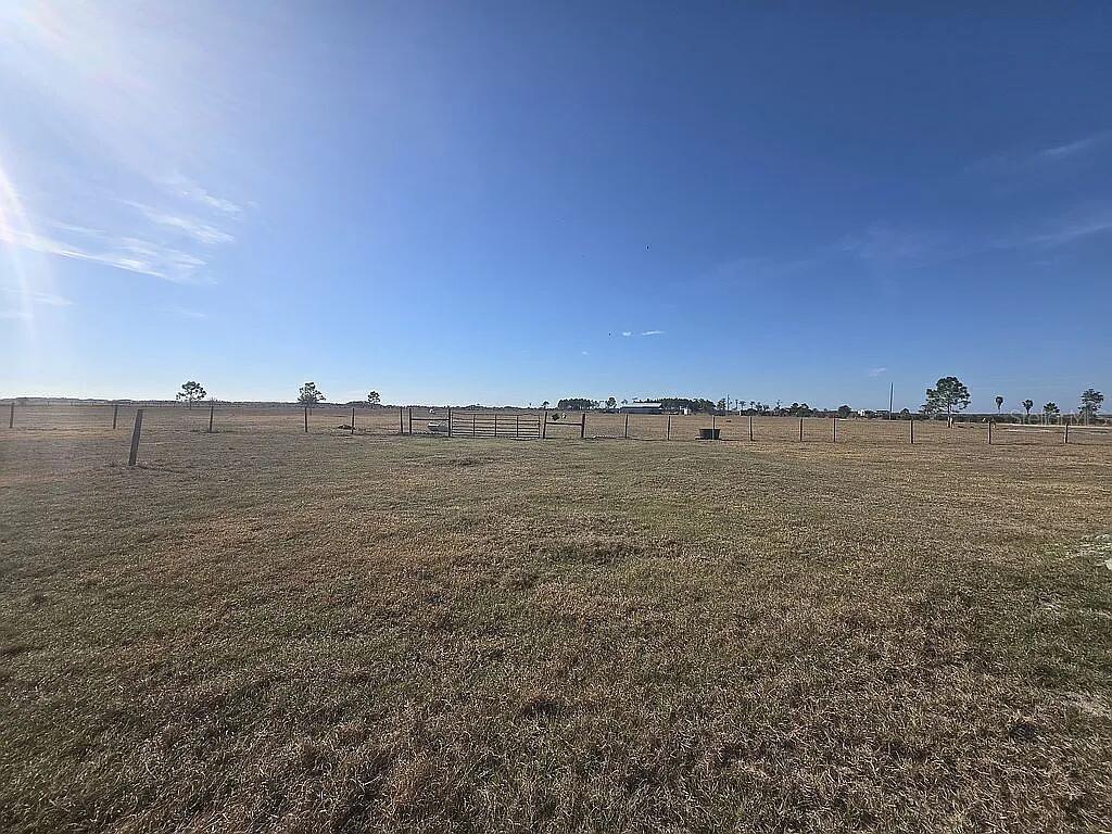 A wide, grassy field is enclosed by a wire fence with a central metal gate — 707 CHIHUAHUA ROAD, SEBRING, FL