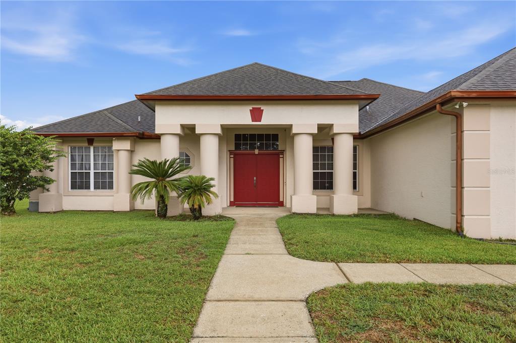 A single-story house with a red double front door, white columns, and a concrete walkway — 20312 MAXIM PKWY, ORLANDO, FL