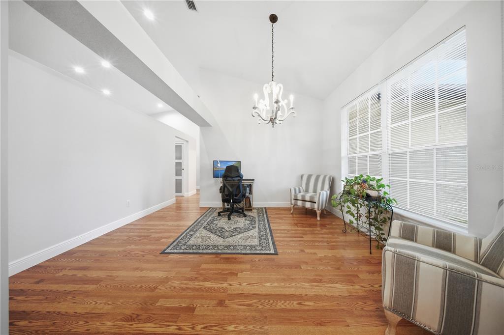 A bright home office features hardwood floors, a chandelier, and a desk near a window — 20312 MAXIM PKWY, ORLANDO, FL
