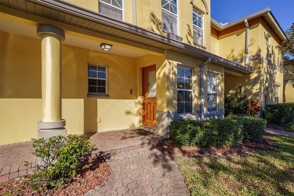 The exterior of a yellow two-story home features a paved walkway and a front porch — 3869 ISLAND WAY, ST PETERSBURG, FL