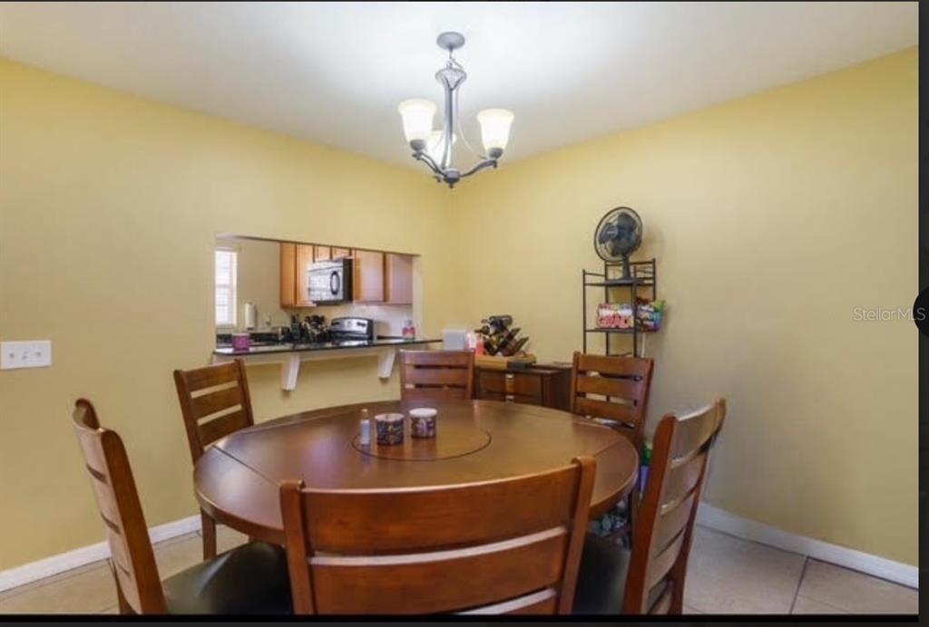 A dining room with a round wooden table, four chairs, and a kitchen pass-through window — 3869 ISLAND WAY, ST PETERSBURG, FL