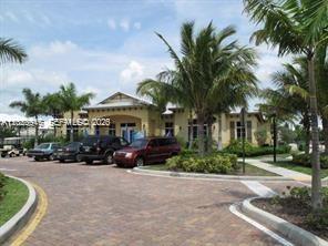 A paved driveway leads to a tan building surrounded by palm trees and parked cars — 2004 Marsh Harbor Dr, Riviera Beach FL 33404, RIVIERA BEACH, FL