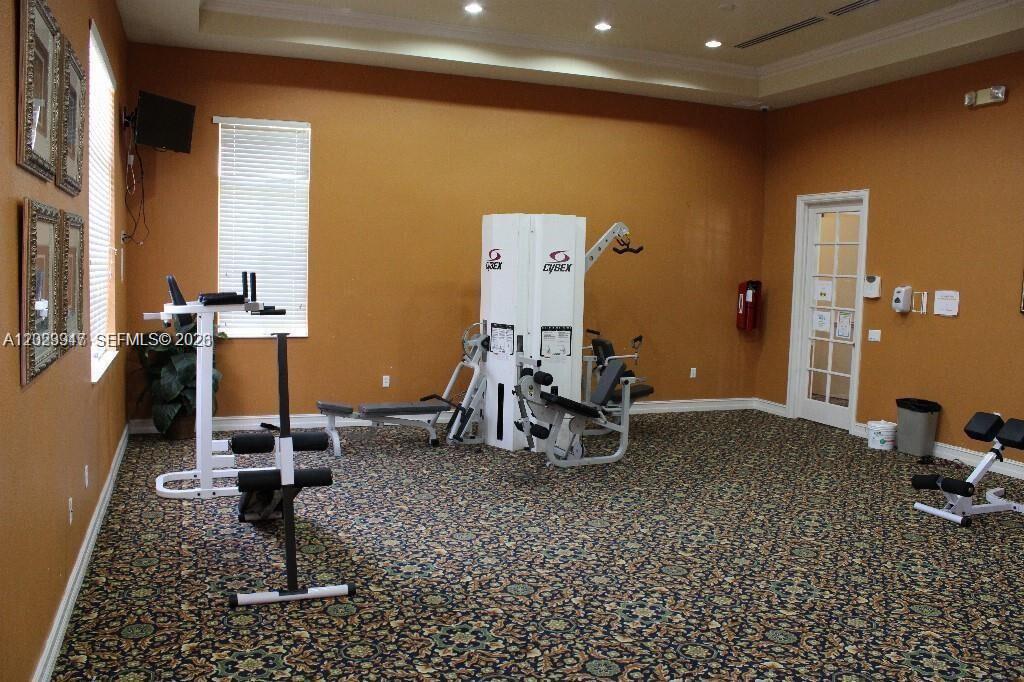A fitness room features patterned carpeting, tan walls, and several pieces of exercise equipment — 2004 Marsh Harbor Dr, Riviera Beach FL 33404, RIVIERA BEACH, FL