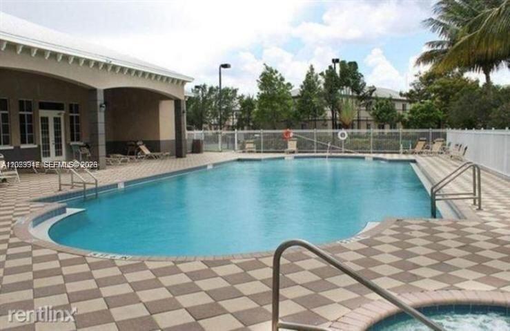 An outdoor swimming pool with a checkered tile deck and a nearby building — 2004 Marsh Harbor Dr, Riviera Beach FL 33404, RIVIERA BEACH, FL