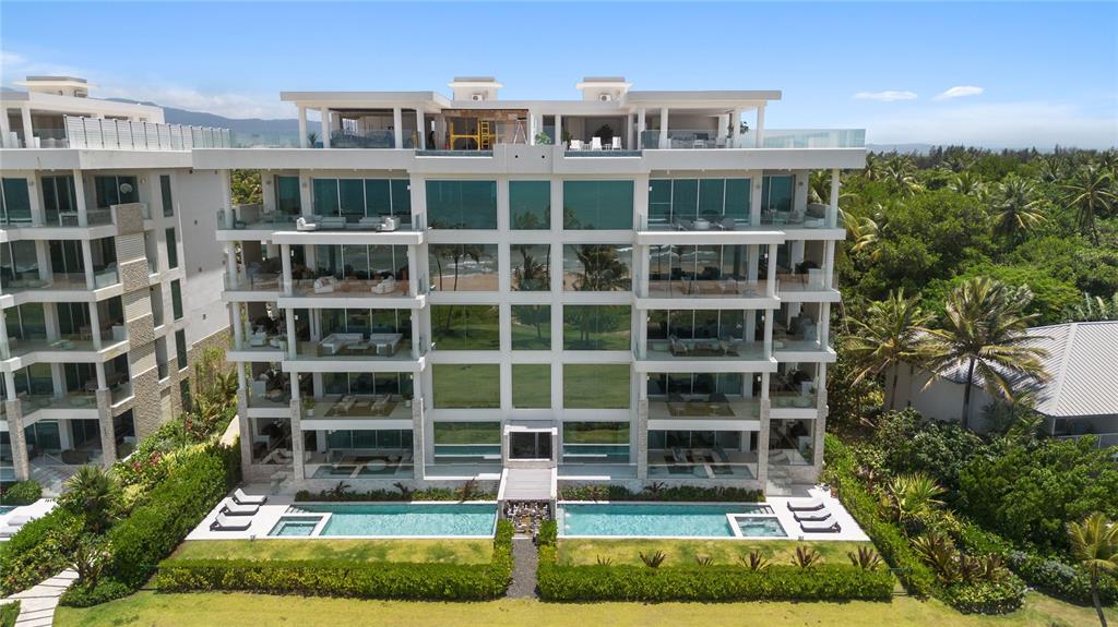 An aerial view of a modern multi-story apartment building with balconies and a ground-level pool — Bahia Beach Resort OCEAN DRIVE UNIT 3102, RIO GRANDE, PR