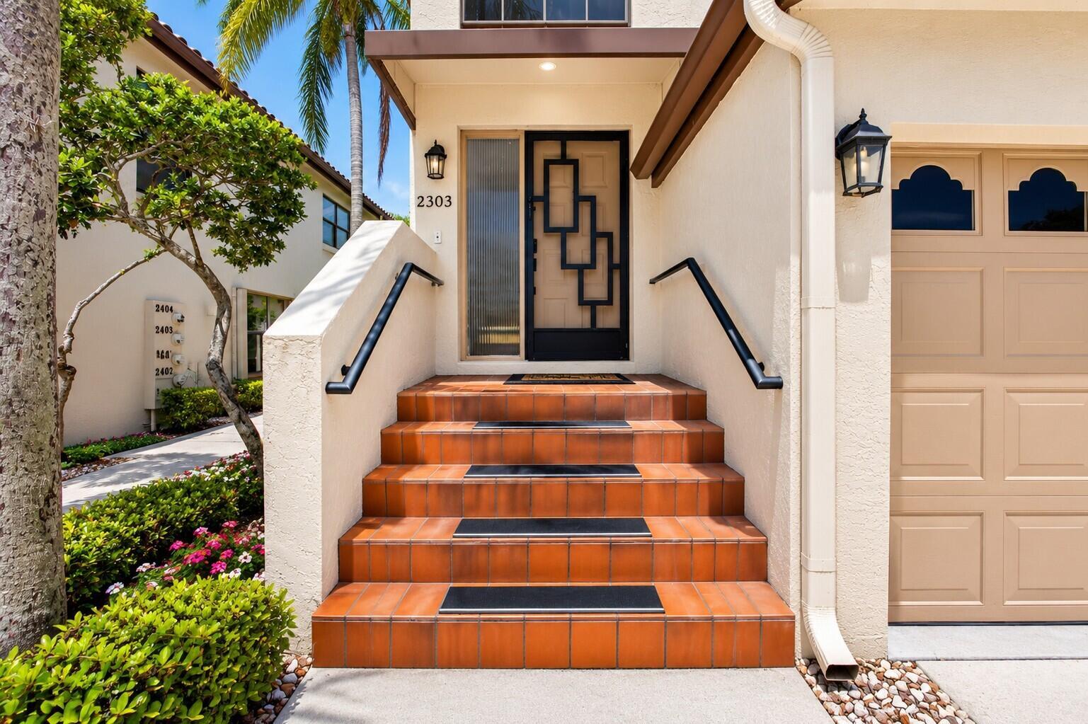 A set of tiled steps with black handrails leads to a front door with geometric detailing — 10039 53rd Way S # 2303, Boynton Beach FL 33437, BOYNTON BEACH, FL