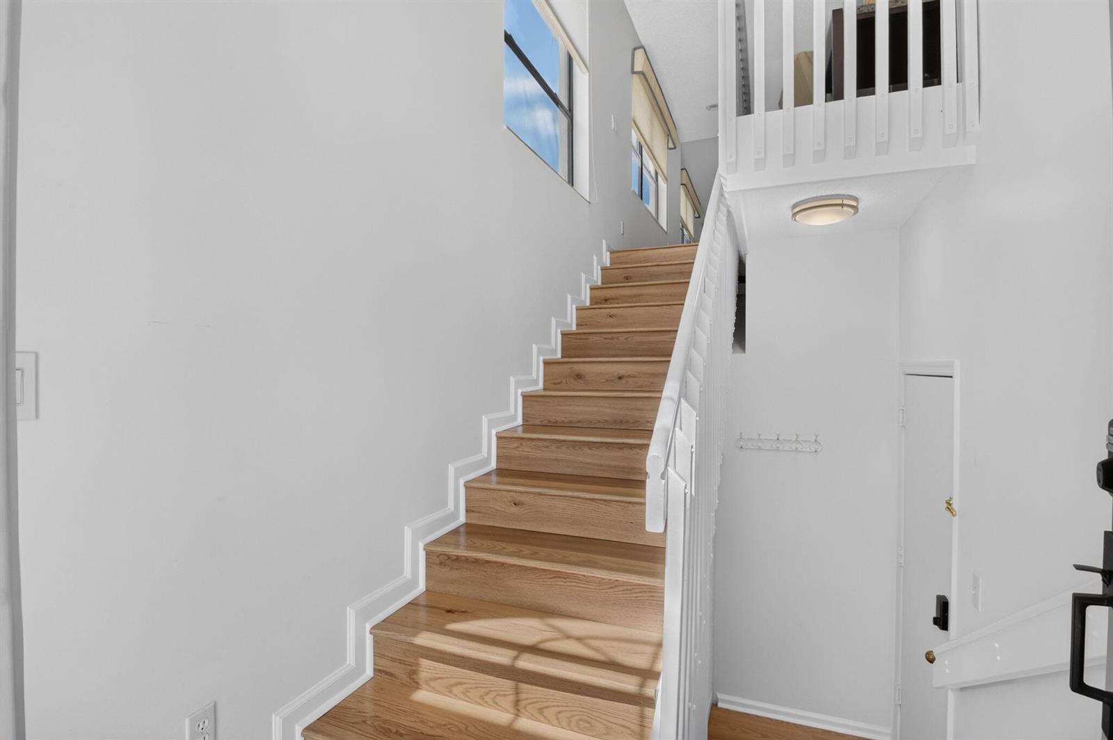 A staircase with light wood treads and white railings leads to an upper level landing — 10039 53rd Way S # 2303, Boynton Beach FL 33437, BOYNTON BEACH, FL