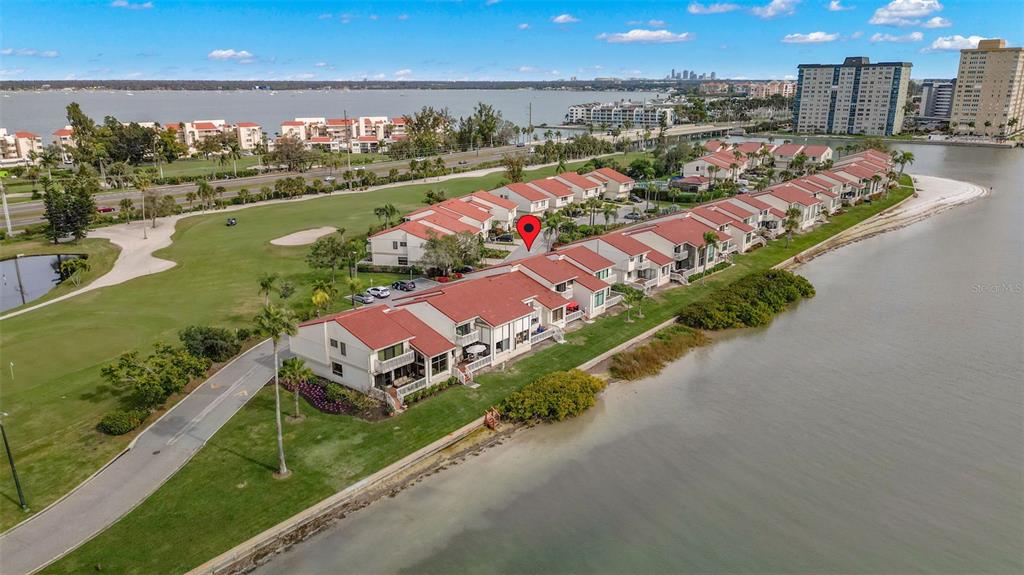 An aerial view shows a row of waterfront townhouses with red roofs beside a golf course — 5668 ESCONDIDA BOULEVARD S, ST PETERSBURG, FL