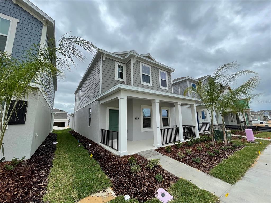 A two-story house with gray siding, a covered front porch, and a landscaped yard — 6098 BLISSFUL STREET, CLERMONT, FL