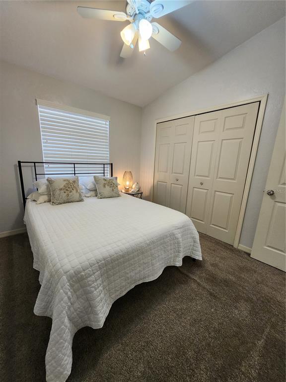 A bedroom features a bed with a white quilt, a ceiling fan, and closet doors — 4801 NW 2ND PLACE UNIT K, GAINESVILLE, FL