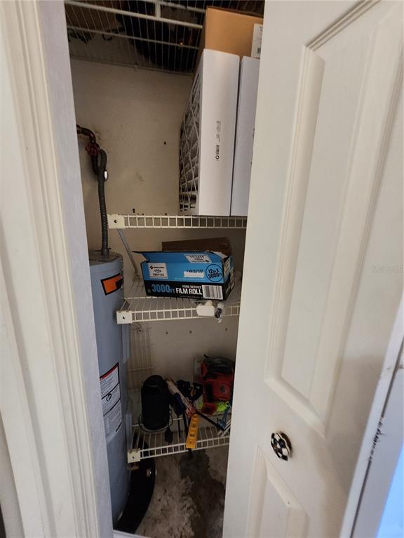 A utility closet contains a water heater, wire shelving, and various household items — 4801 NW 2ND PLACE UNIT K, GAINESVILLE, FL