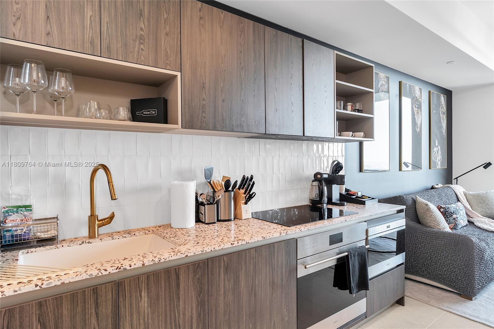 A modern kitchen features wood-grain cabinets, a speckled countertop, and a white tiled backsplash — 601 NE 1st Ave # 4907, Miami FL 33132, MIAMI, FL