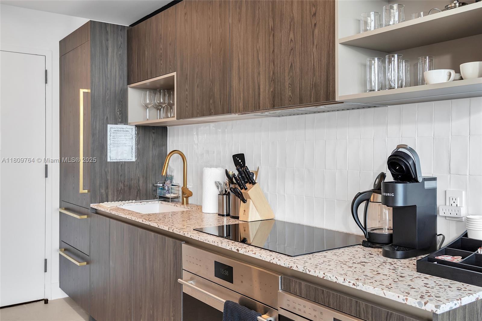 A modern kitchen features wood-grain cabinetry, a speckled countertop, white tile backsplash, and stainless appliances — 601 NE 1st Ave # 4907, Miami FL 33132, MIAMI, FL
