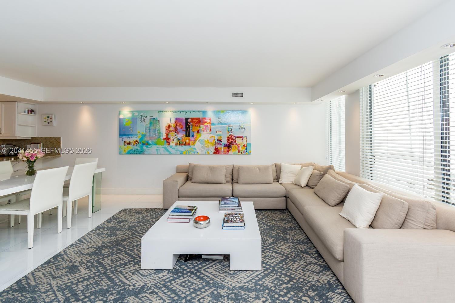 A living room features a large beige sectional sofa, a white coffee table, and colorful art — 425 Grapetree Dr # 206, Key Biscayne FL 33149, KEY BISCAYNE, FL