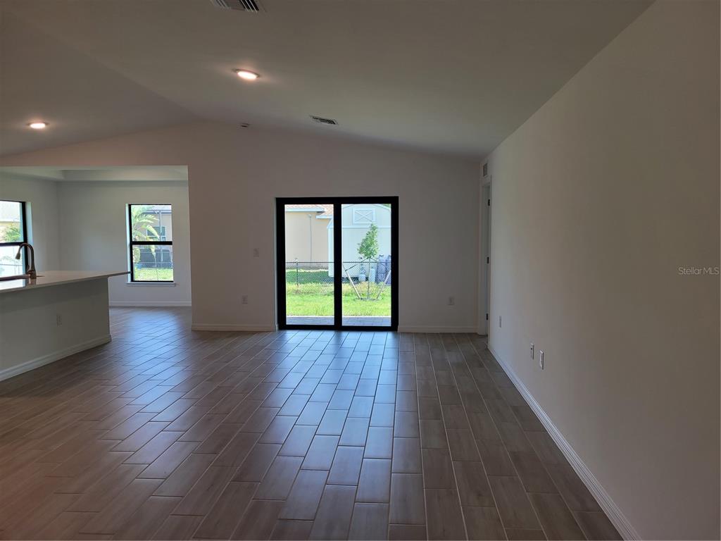 An open-concept living area features light-colored tile flooring, white walls, and sliding glass patio doors — 11383 BAGGOT AVENUE, ENGLEWOOD, FL