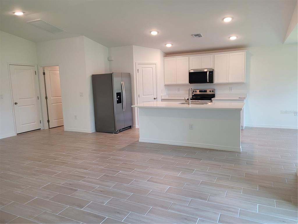 A kitchen with white cabinets, a stainless steel refrigerator, and a central island — 11383 BAGGOT AVENUE, ENGLEWOOD, FL