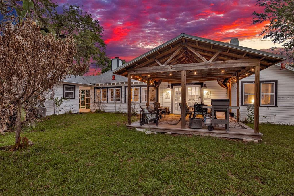 A white house with a wooden covered patio and a grassy yard at sunset — 801 CANAL STREET, NEW SMYRNA BEACH, FL