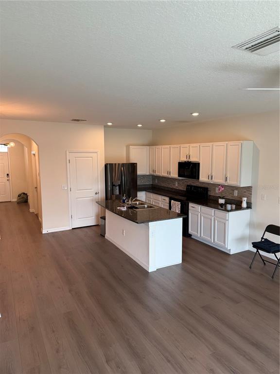 A kitchen with white cabinets, a dark island countertop, and light wood-look flooring — 1833 HOVENWEEP ROAD, WESLEY CHAPEL, FL