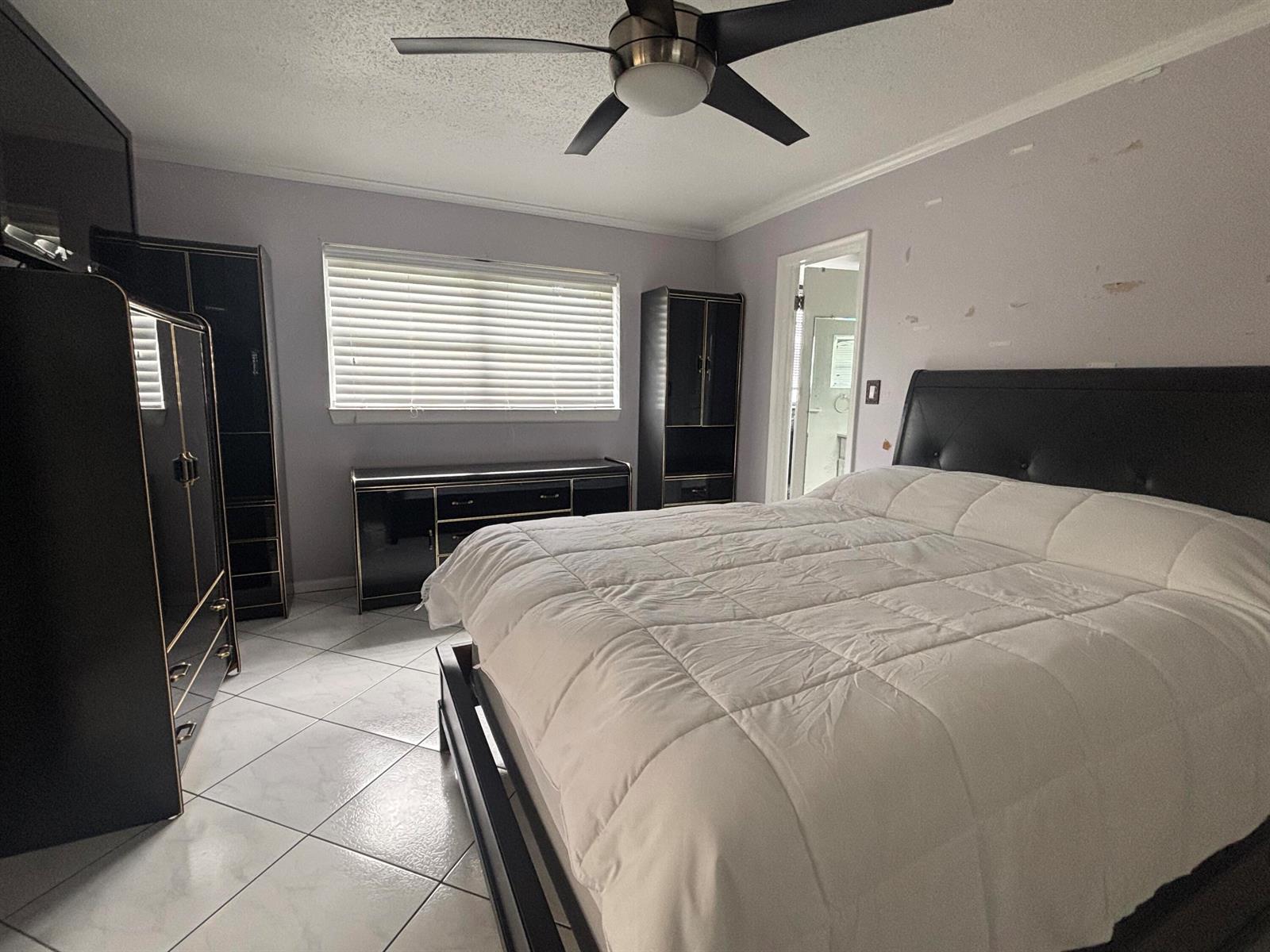 A bedroom features a black bed frame, matching furniture, white tile floors, and a ceiling fan — 81 Windsor D, West Palm Beach FL 33417, WEST PALM BEACH, FL