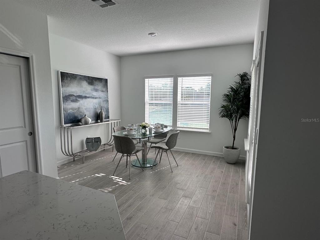 A dining area features a glass table, four gray chairs, a console table, and tile flooring — 12345 NW 137 WAY, ALACHUA, FL