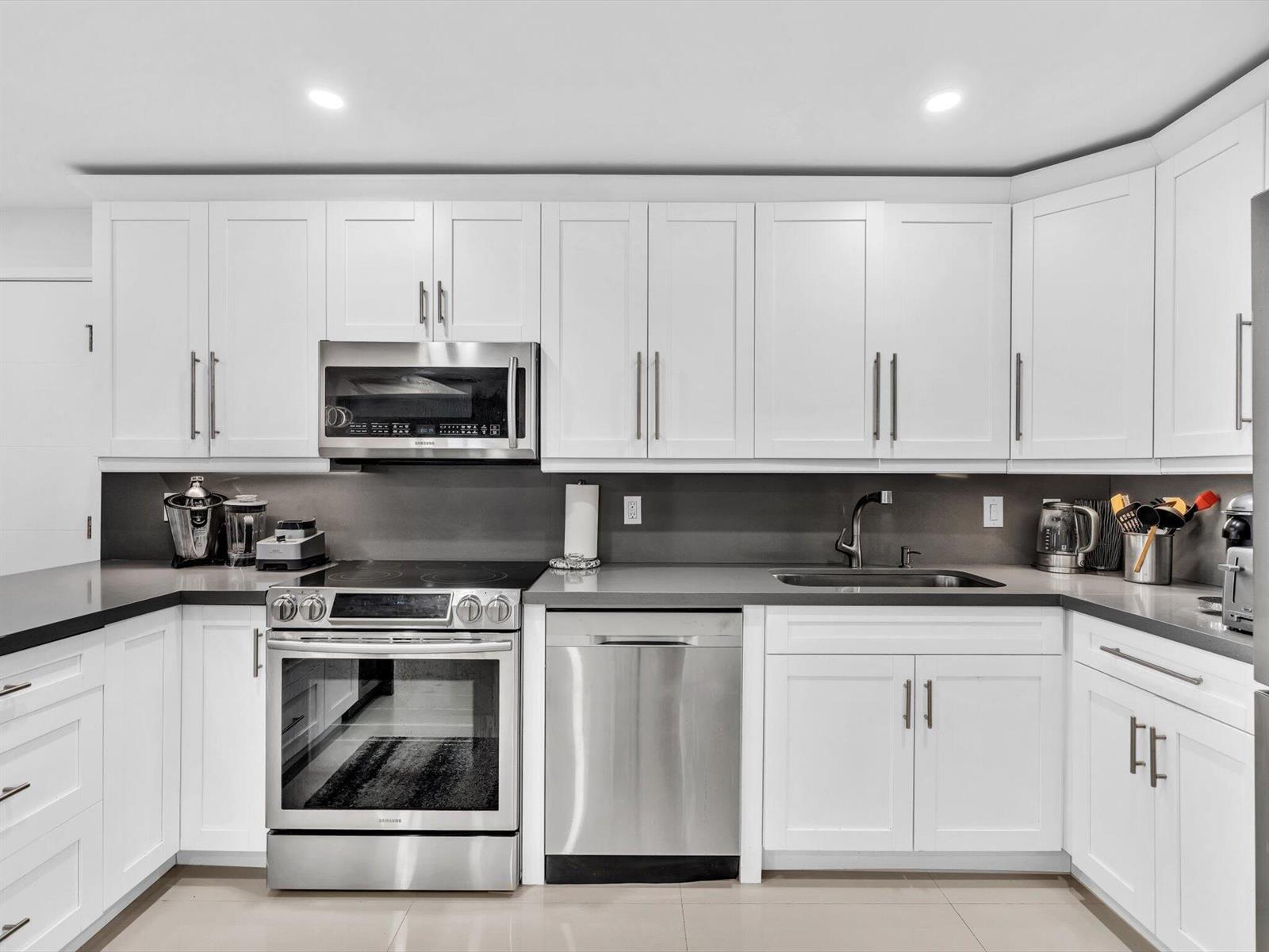 A modern kitchen features white cabinets, stainless steel appliances, and dark gray countertops — 3440 S Ocean Boulevard # 307n, Palm Beach FL 33480, PALM BEACH, FL