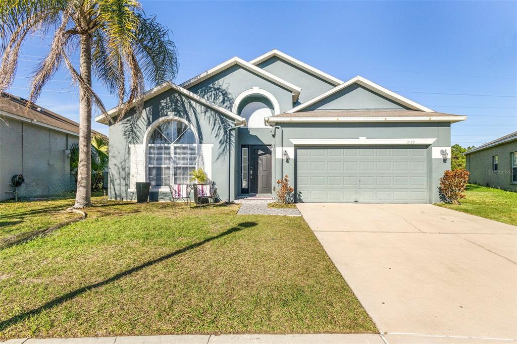 A single-story house with a gray exterior, a two-car garage, and a palm tree — 1739 CANOE CREEK FALLS DRIVE, ORLANDO, FL