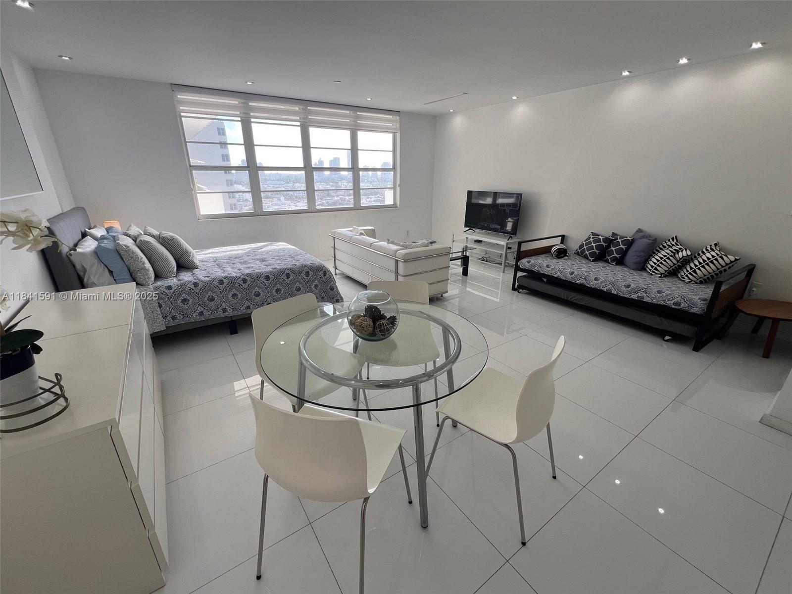 A studio apartment features a bed, dining set, sofa, and tile flooring with city views — 100 Lincoln Rd # 1601, Miami Beach FL 33139, MIAMI BEACH, FL