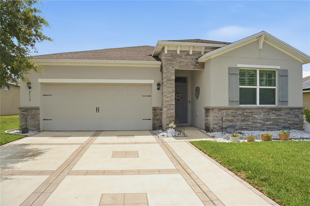 A single-story house features a stone facade, a two-car garage, and a paved driveway — 9152 SW 60TH COURT ROAD, OCALA, FL